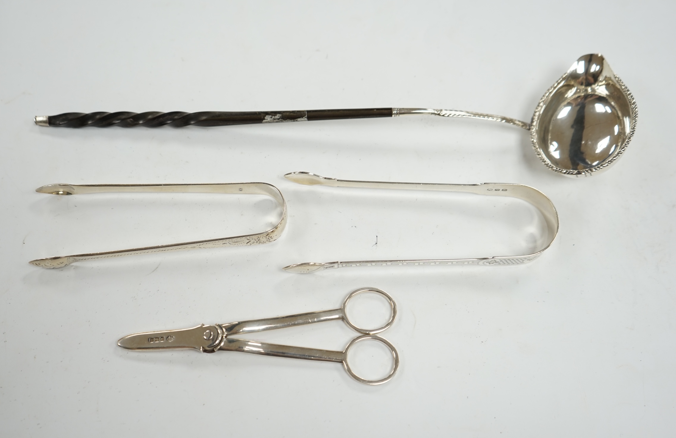 A pair of George V silver grape scissors, by William Hutton & Sons, two pairs of silver sugar tongs and a Georgian silver punch ladle. Condition - poor to fair